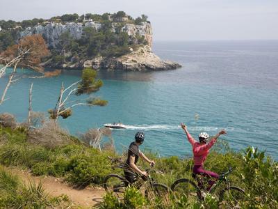 Zwei Radfahrer genießen die Küstenlandschaft mit Blick auf das Meer und Klippen.