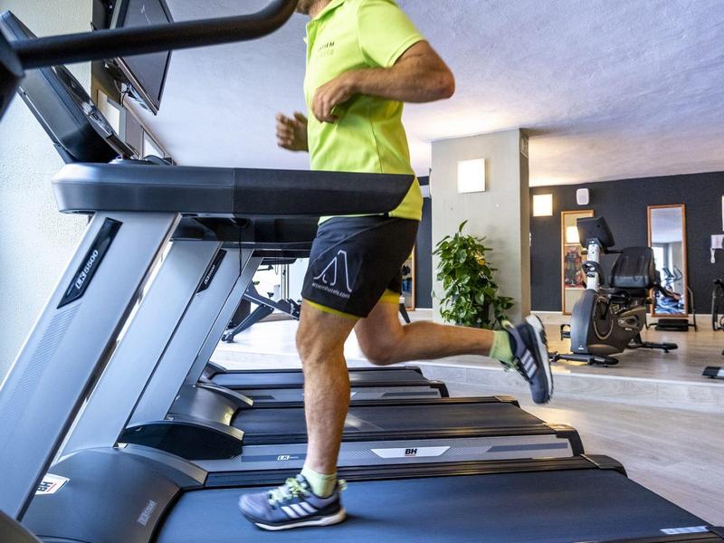 Person running on a treadmill in a modern gym with fitness equipment around.