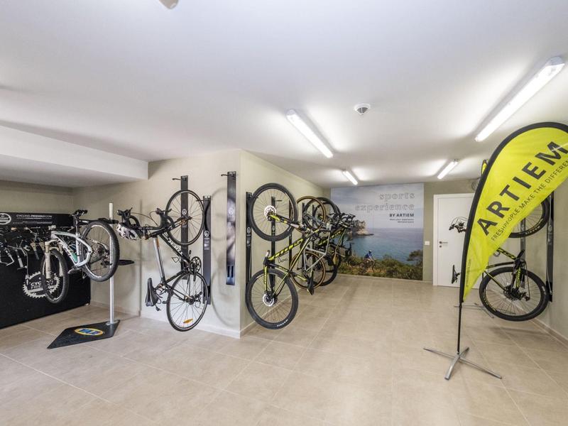 Modern bike rental room with bikes hanging on white walls and tiled floor.