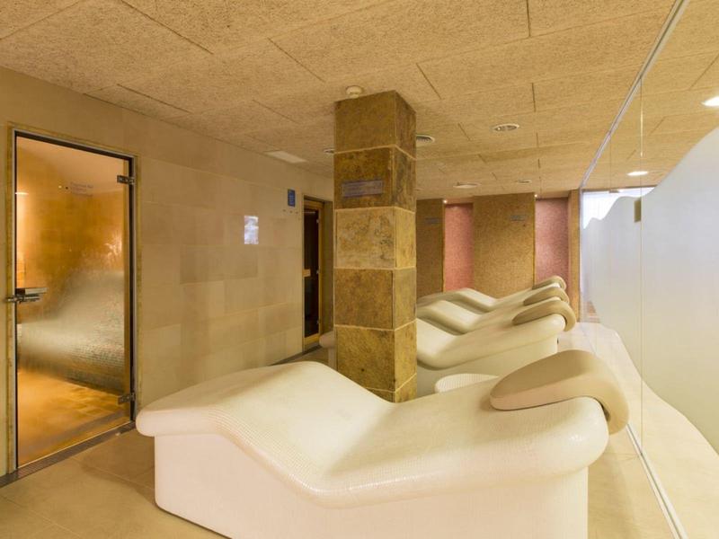 Modern hotel corridor with chaise lounges and soft lighting along the wall.