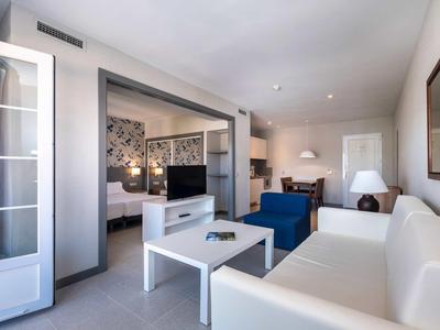 Salon moderne avec canapé blanc, fauteuils bleus et chambre ouverte.