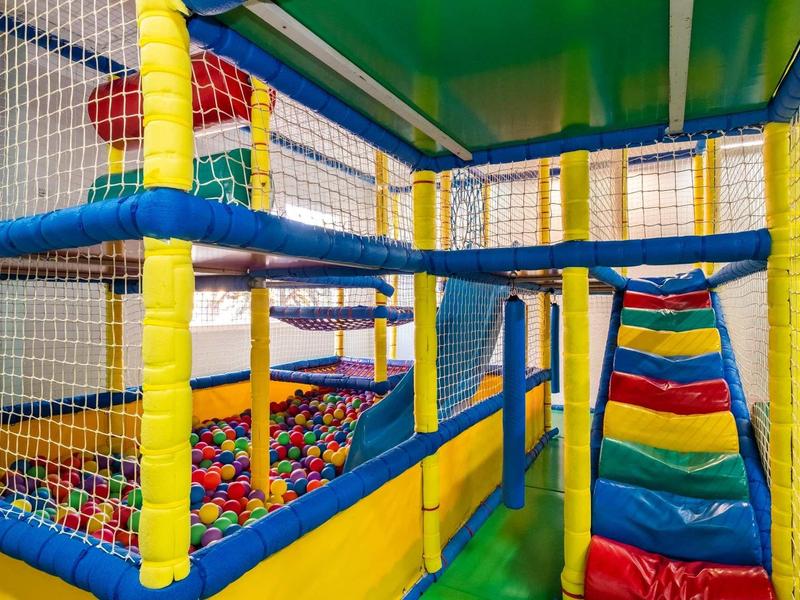 Aire de jeux intérieure colorée pour enfants avec toboggan et piscine à balles dans une structure softplay.