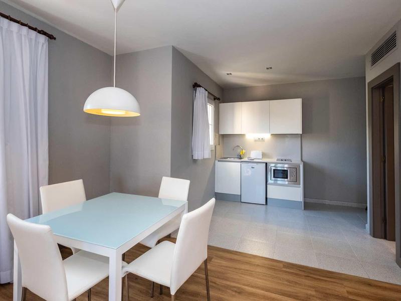 Salle à manger moderne avec table blanche et chaises à côté d'une cuisine ouverte