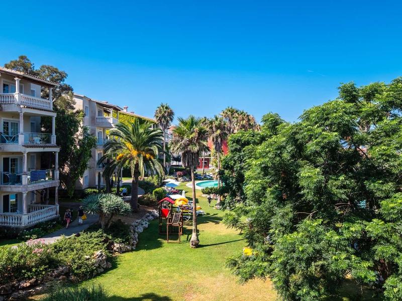 Bâtiment d'hôtel entouré de palmiers et de verdure luxuriante par temps ensoleillé