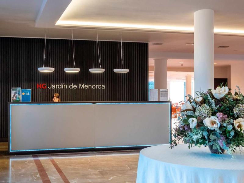 Réception d'hôtel avec comptoir et arrangement floral sur une table.