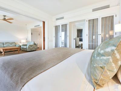 Bright hotel room with large bed, sofa, and wooden furniture in a warm, inviting style.