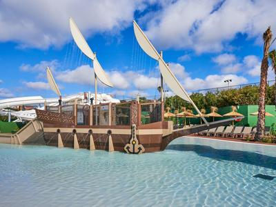 A water playground shaped like a sailing ship with slides and a pool under blue sky.