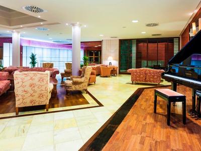 Spacious hotel lounge area with cozy sofas, armchairs, and a black grand piano.