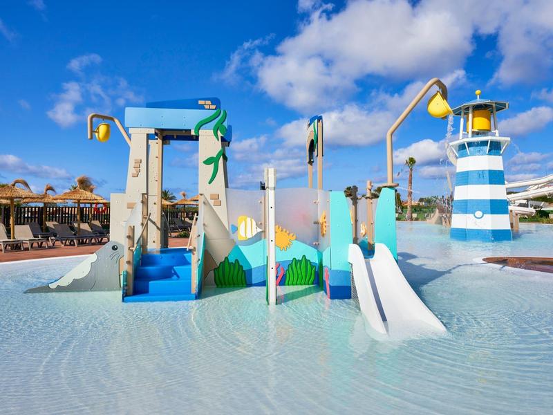 Colorful water playground with slides and water sprayers under a blue sky.