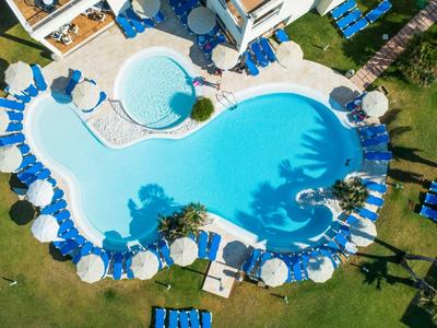 Top view of a freeform pool with umbrellas and lounge chairs in a hotel garden.