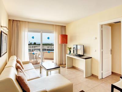 Bright living room with sofa, TV, and access to a balcony terrace with sea view.