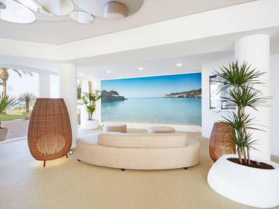 Bright living room with large beach mural, round sofa, hanging chairs, and potted plants.