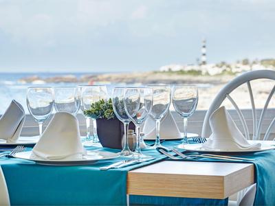 Eleganter gedeckter Tisch mit weißen Servietten und Gläsern vor einem Meerblick.
