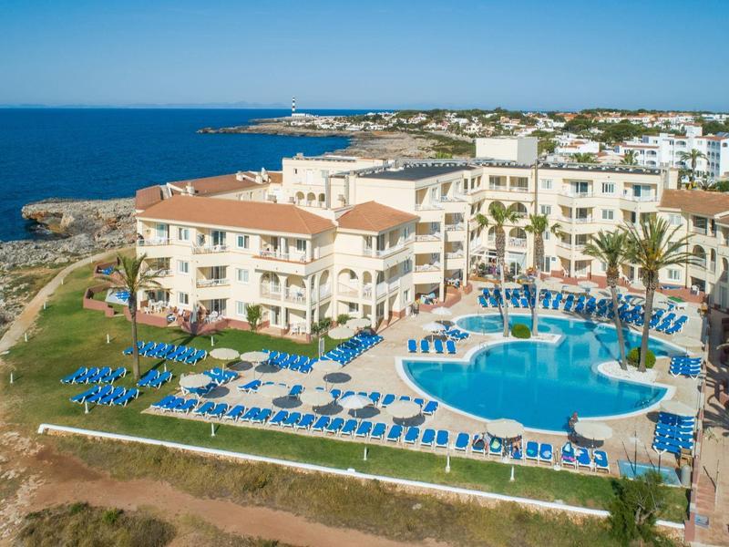 Coastal hotel with pool, sun loungers, and sea view.