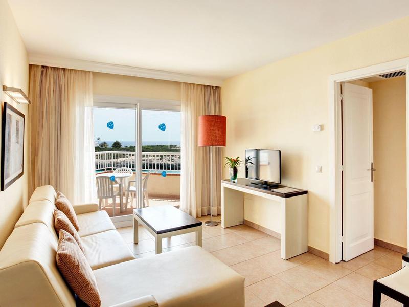 Bright living room with sofa, TV, and access to a balcony terrace with sea view.