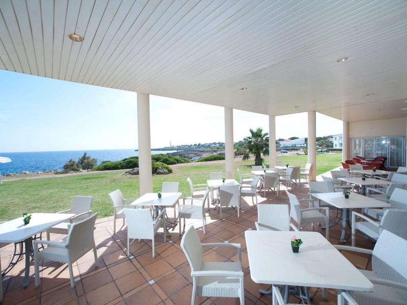 Open restaurant area with white chairs and tables overlooking the sea.