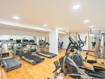 Modern gym with treadmills, cross trainers, and wooden flooring in a hotel.