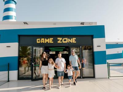 Family leaving game zone of a modern blue and white holiday hotel in sunny weather.