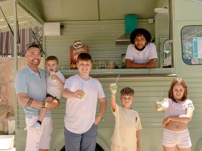 Family in front of a light green food truck holding ice pops.