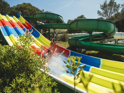 Multilane colorful water slide and green tube slide outdoors in a leisure area.