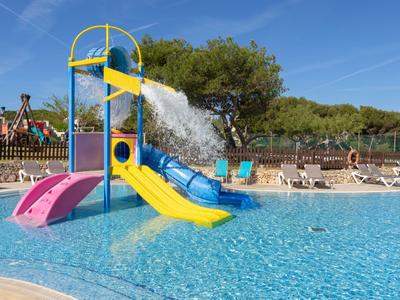 Colorful water playground with slides in a clear hotel pool under a blue sky.