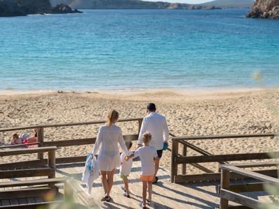 Three people walking on the beach towards the sea on a sunny day.