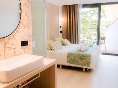 Brightly decorated hotel room with double bed, balcony, and modern sink.