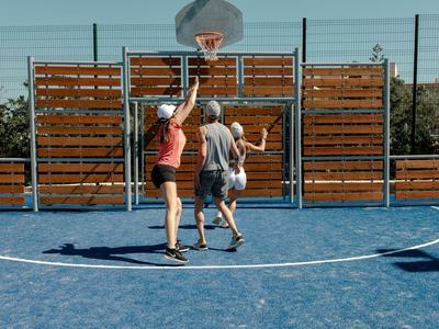 Two women playing basketball on a blue outdoor court in sunny weather.