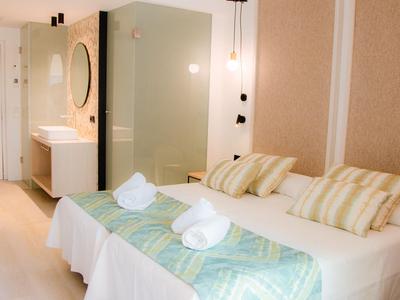 Bright hotel room with double bed, striped pillows, and modern bathroom facilities.