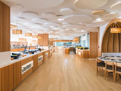Bright, modern hotel dining area with wood accents and round ceiling lights.