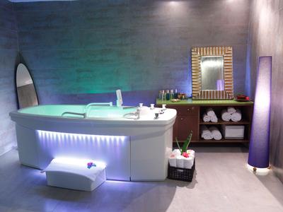 Modernes Badezimmer mit freistehender Badewanne, Leuchtdetails und Spiegel mit Holzrahmen.