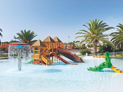 Dziecięcy park wodny z kolorową konstrukcją do zabawy, atrakcjami wodnymi i palmami pod czystym niebem