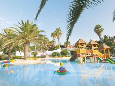 Kinderpool mit Wasserspielplatz, Rutschen und Palmen in einem Resort bei sonnigem Wetter