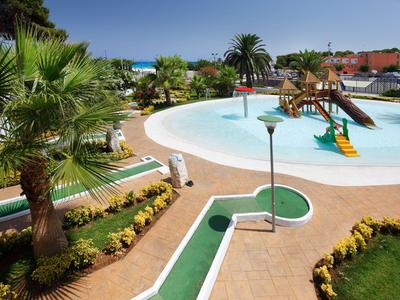 Außenpoolbereich mit Wasserrutsche, Minigolfbahn und Palmen in einem Resort.