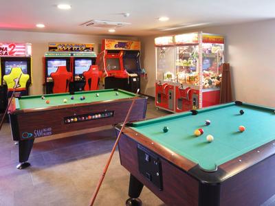 Ein heller Freizeitraum mit Billardtisch, verschiedenen Arcadespielen und einem Greifautomaten.