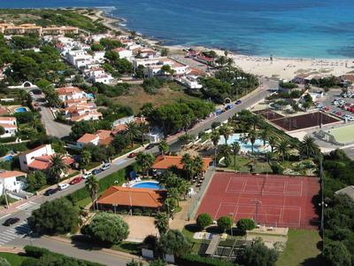 Widok z lotu ptaka na nadmorską wioskę z plażą, kortami tenisowymi i terenami zielonymi.