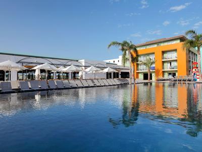 Piscina dell'hotel con lettini e edificio arancione sotto un cielo sereno