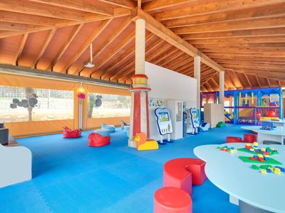 Jasny i kolorowy kącik zabaw dla dzieci z drewnianym sufitem i niebieskimi płytkami podłogowymi w hotelu.