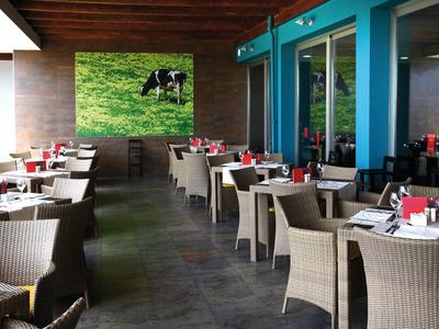 Nowoczesna restauracja z wiklinowymi krzesłami i nakrytymi stołami przy niebieskich ścianach.