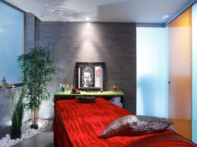 Nowoczesna sypialnia z czerwoną łóżkiem i roślinami przy szarej ścianie.