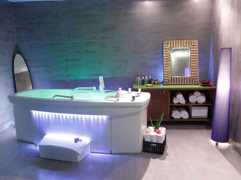 Nowoczesna łazienka z podświetlaną wanną, lustrem i dekoracyjnym oświetleniem.