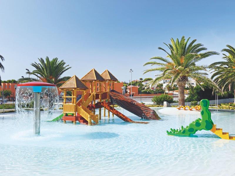 Dziecięcy park wodny z kolorową konstrukcją do zabawy, atrakcjami wodnymi i palmami pod czystym niebem