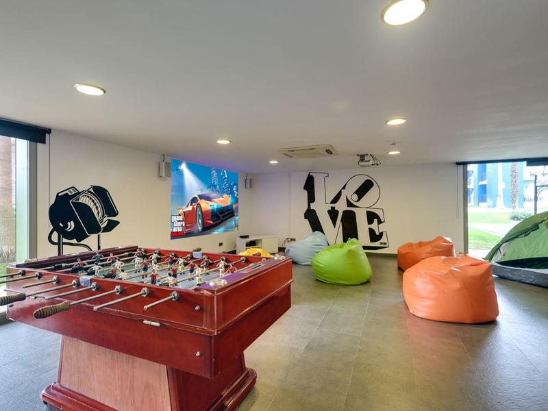 Nowoczesna sala gier z piłkarzykami, kolorowymi pufami i małym namiotem.