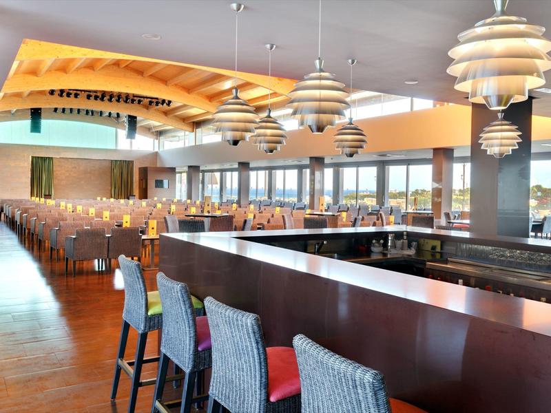 Jasny bar hotelowy z nowoczesnymi stołkami i dużymi oknami z widokiem na miasto.