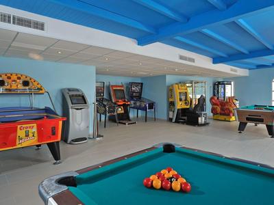 Herna s kulečníkem, flippery a arkádovými hrami pod modrým stropem.