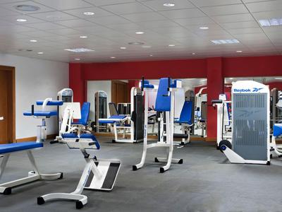 Ein moderner Fitnessraum mit verschiedenen Trainingsgeräten und Spiegelwand.