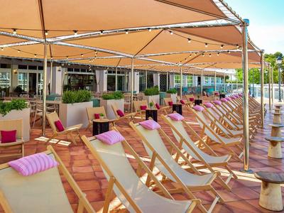 Řada lehátek s barevnými polštáři pod sluneční ochranou na terase