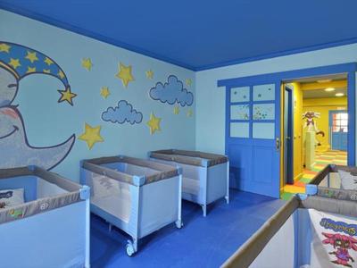 Světle modrá místnost s postýlkami a nástěnnou malbou měsíce, vhodná pro děti v hotelech.