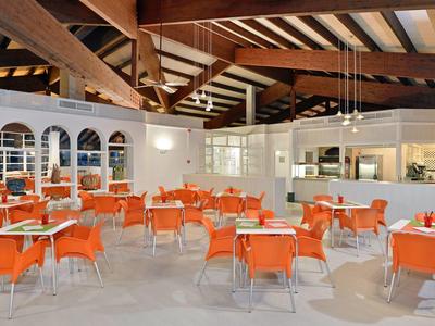 Prostorná jídelna s oranžovými židlemi a dřevěnými trámy na stropě