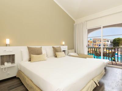 Světly hotelový pokoj s manželskou postelí a balkonem s výhledem na bazén